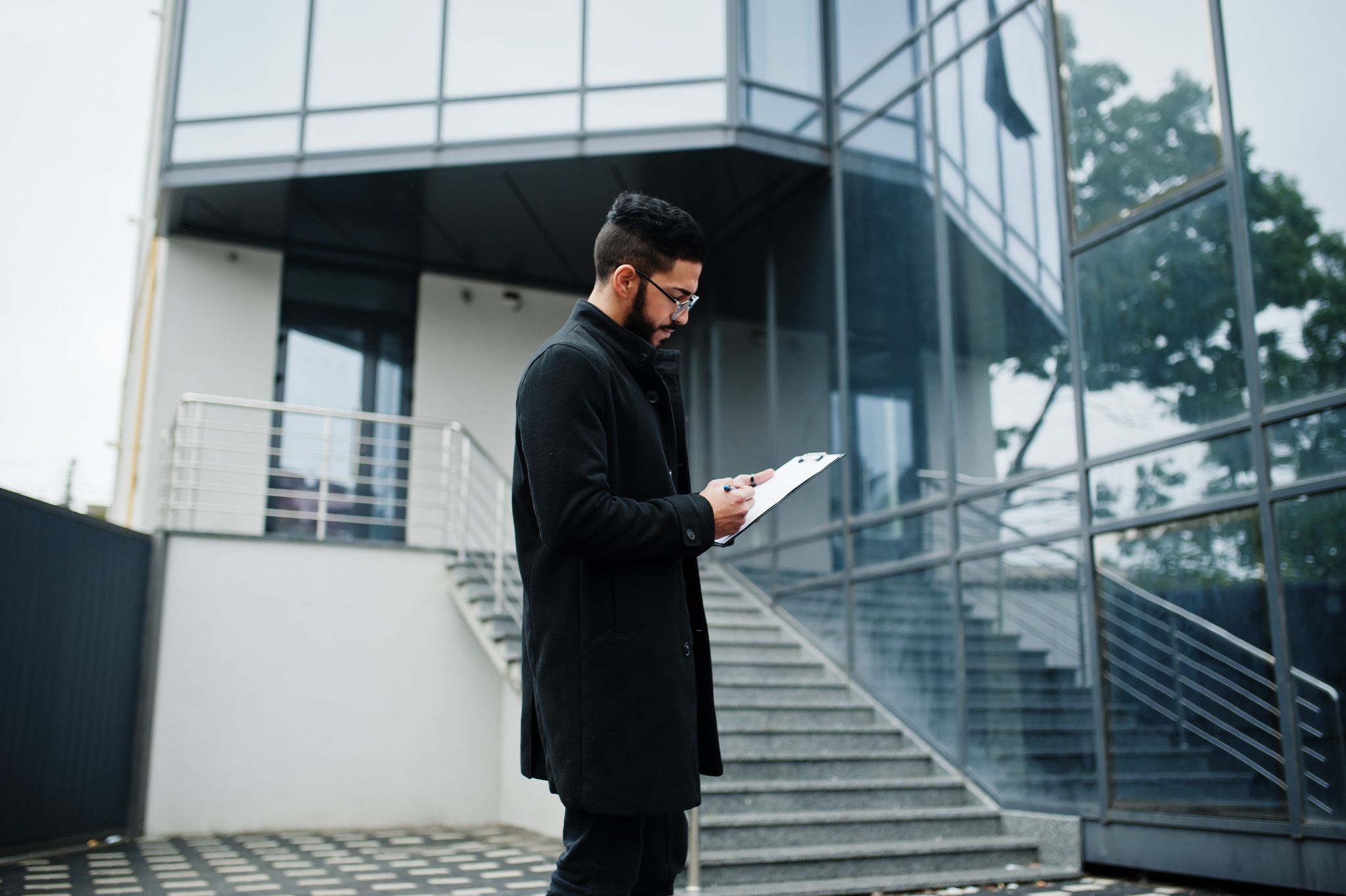 middle eastern man wear black coat, eyeglasses, writing contract